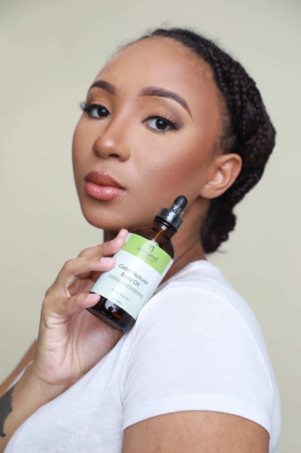 Customer holding Calmi Natural Body Oil near her shoulder